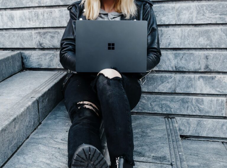 Mulher Na Jaqueta Preta E Calcas Pretas Sentadas Em Escadas De Concreto Usando Microsoft Surface Laptop KxCAa7wpzu0